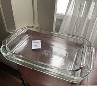 Clear Pyrex glass 4 quart rectangular baking dish with side handles on wooden surface, lot number sticker visible on inside bottom.