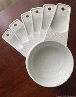 Set of 6 nesting Tupperware measuring cups fanned out to show size increments embossed on handles