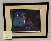 Framed lithograph showing Genie and Aladdin characters with numbering 3867/35000 and Disney commemorative seal.