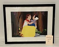 Framed lithograph showing Snow White and Prince Charming from Disney's Snow White and the Seven Dwarfs. The couple is embracing in a forest scene. Black frame and white mat.