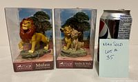 Photo showing two boxed Lion King figurines: Mufasa and Simba with Nala, next to a soda can for size reference.