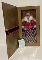 Full view of Barbie doll in original gold box with black and pink horizontal stripe, doll in pink and black attire with white fur trim.