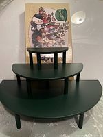 Three-tiered green semi-circular display risers stacked together showing the graduated stepped design with original box in background