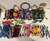 Top-down photo showing an assortment of Candlewick yarn skeins and hanks in multiple colors arranged in rows along with three embroidery hoops and some needlework pattern cards.