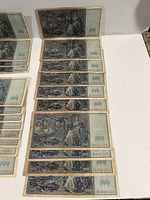 Photo showing a collection of 13 German 100 Mark banknotes arranged in rows, all featuring the same design and sequential serial numbers.