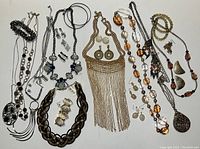 Full view of lot with various necklaces, earrings and bracelets arranged on white background.
