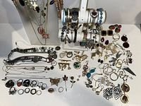 Wide view showing numerous earrings, rings, bracelets, necklaces displayed on stands and laid out flat.