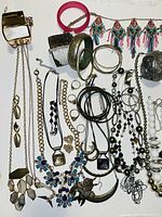Photo of mixed jewelry featuring bracelets, necklaces, earrings, and rings arranged flat on white background