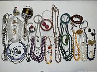 Summary image showing full assortment of necklaces, bracelets, earrings, and brooches arranged flat on white surface.