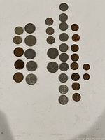 Thirty foreign coins arranged in columns on a white background showing size and shape variety.