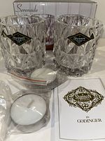 Two Shannon Crystal votive candle holders in front of box, with tea light candles and instruction booklet.