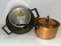 Image showing the two copper saucepans side by side, small one with lid, paper labels visible inside.