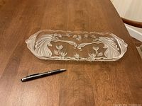 Rectangular crystal serving dish on wood surface with pen for size reference