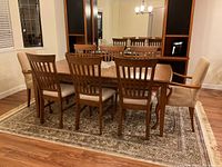 Nine-piece wooden dining set on area rug, full view of table and chairs