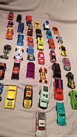 Overview of the 38 die-cast metal cars arrayed on a flat surface, showing various models, colors, and sizes including race cars