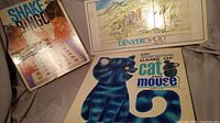 Photo showing the three vintage board games Shake Bingo, Game of Cat and Mouse, Denveropoly 1994 in used condition on display.
