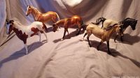 Wide view of all 5 Breyer horse figurines arranged on a fabric surface, showing colors and pose variations.