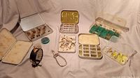 Overall view of vintage fly fishing kit showing multiple fly boxes, reel, clippers, and small tins.