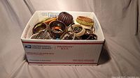 Photo of large USPS Priority Mail box filled with assorted bracelets of different sizes and colors showing top view of bracelets inside