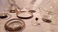 Overview of antique sterling silver bases combined with crystal pieces including pitcher, candy dish, sugar bowl, gravy/creamer bowl, small pitcher, salt shaker, ashtray, and glass plate.