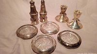 Overall view of 2 sterling silver candlesticks, 2 salt and pepper shakers, and 4 sterling silver ashtrays with crystal centers