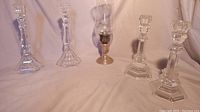 Wide shot of all 5 items including 2 Tiffany & Co. crystal candlesticks on left, sterling silver candle lamp in center, and 2 regular crystal candlesticks on right.