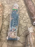 Rolled blue floral patterned rug wrapped in plastic viewed from top end.