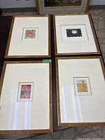 Four framed floral prints arranged on floor, showing overall condition and framing
