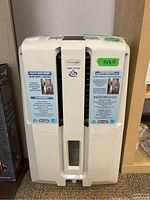 Front view of white DeLonghi dehumidifier unit with pump system, showing informational stickers about heavy duty pump and 45 pints/day capacity.