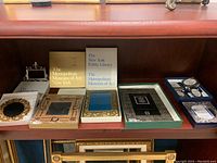 Shelf of assorted picture frames including boxed sets from The Metropolitan Museum of Art and The New York Public Library, and decorative ornate frames.