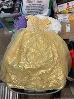 Yellow Disney princess dress, shiny fabric with gold pattern, spread out on chair.