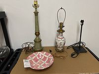 Full lot of three lamps and ceramic bowl on a brown surface against white wall