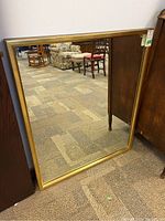 Front view of the rectangular wall mirror showing gold-colored composite frame and clear reflective surface.