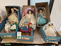 View of all dolls in original Madame Alexander doll company boxes, showing dolls in various costumes including a bride, blue dress doll, and several smaller dolls