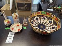 All porcelain items displayed on table including large Royal Crown Derby octagonal bowl with colorful Imari pattern and smaller cups and saucers.