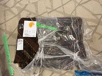 Folded area rug partially wrapped in plastic showing overall pattern and fringe corner