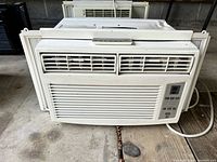 Front view of the white window air conditioner unit showing ventilation grills and control panel