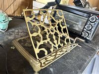 Angled side photo showing brass book holder with decorative cut-out design.