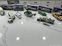Photo showing a wide view of the Hess truck collection including multiple truck models and some boxed items in the background.