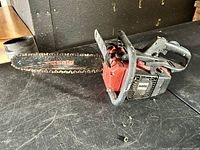 Full view of the Solo 632 chainsaw showing red body, black handle, and attached metal bar chain with visible wear and dirt.