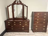 Wide view showing the wooden dresser with large tri-fold mirror and tall chest of drawers next to it.
