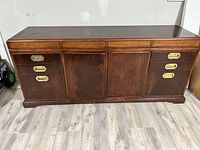 Front view of the wooden office cabinet showing a polished brown finish, three central door compartments, and six brass-handle drawers.