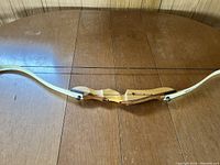 Side profile showing the entire recurve bow with wooden handle and limbs, and attached bowstring.