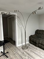 Full view of the sectional lamp with five arched brushed nickel arms extending from the base