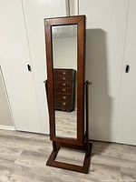 Full view of the standing wooden framed full-length mirror with a rectangular reflective surface.