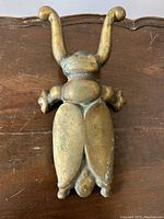 Front view of solid brass horned beetle door stop showing patina and inscription.