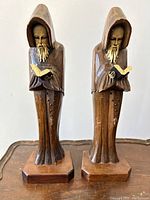 Front view of paired carved wood praying monk bookends, showing detailed faces, robes, and books held.