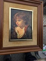 Framed art print of a blond haired boy with wooden frame, beige mat, and gold inner trim, shown at an angle