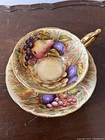 Top view of cup nested in saucer showing full fruit motif and gold trim