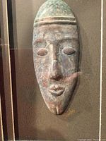 Close-up image of the small elongated African mask sculpture with earthy colors and artist signature.